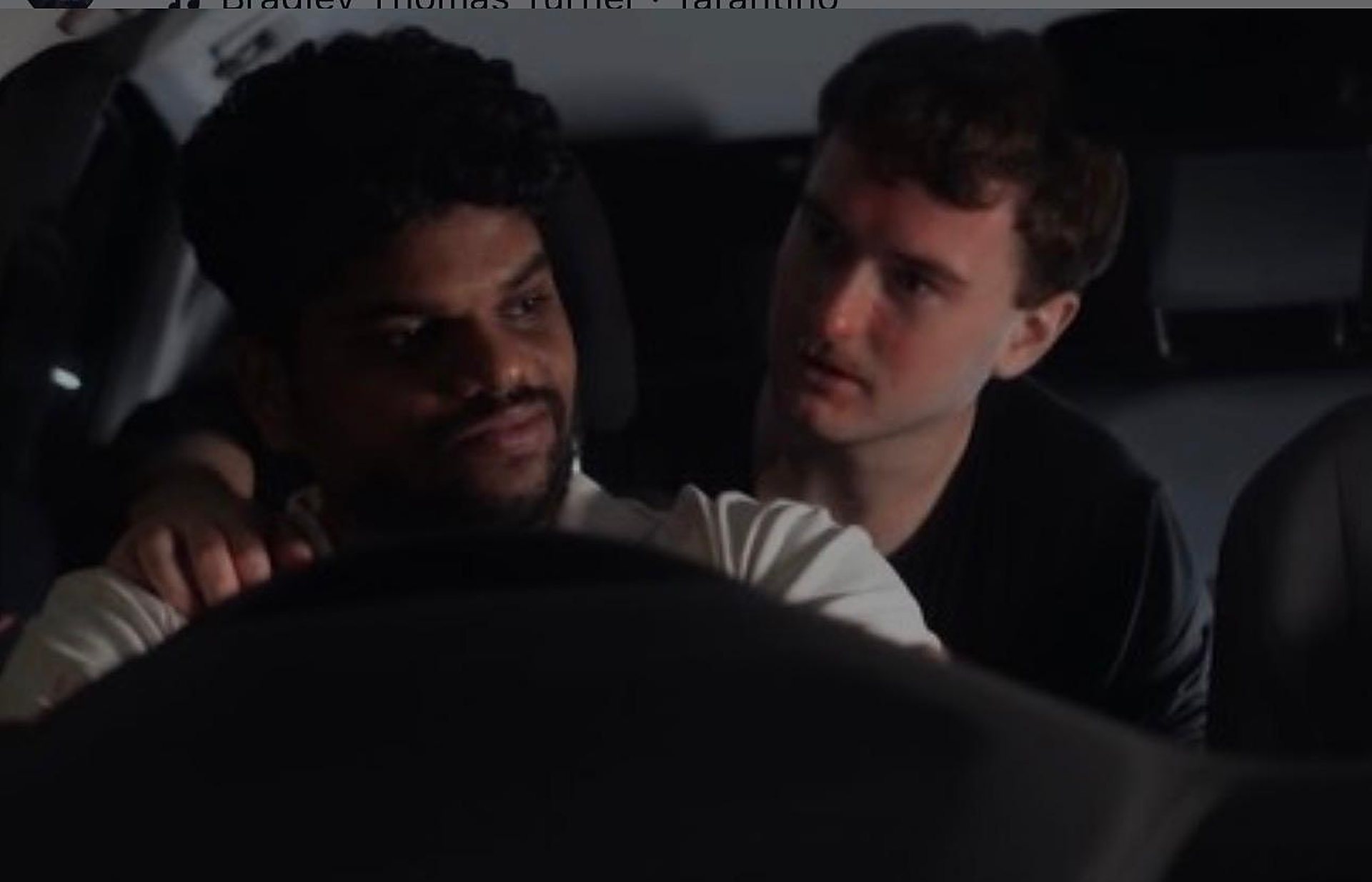 Andrei in the back seat of a car at night, leaning toward the driver