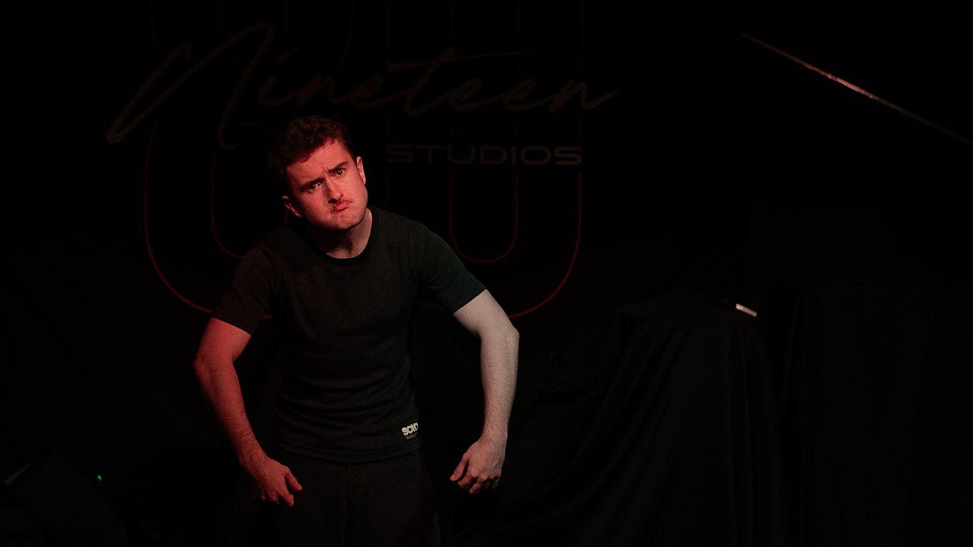 Andrei alone on a dark stage in Unbecoming