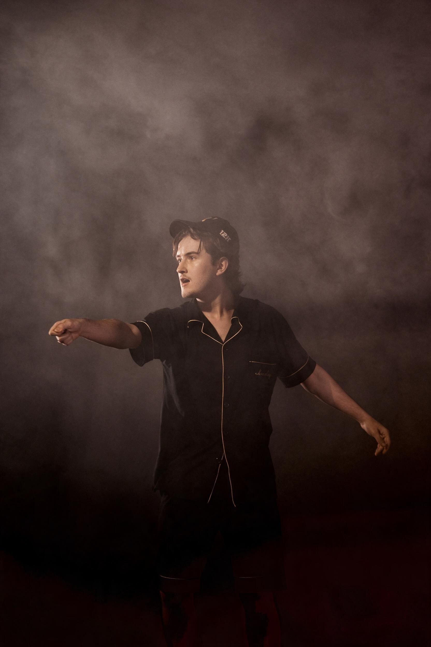 Andrei in stage smoke, pointing out into the dark