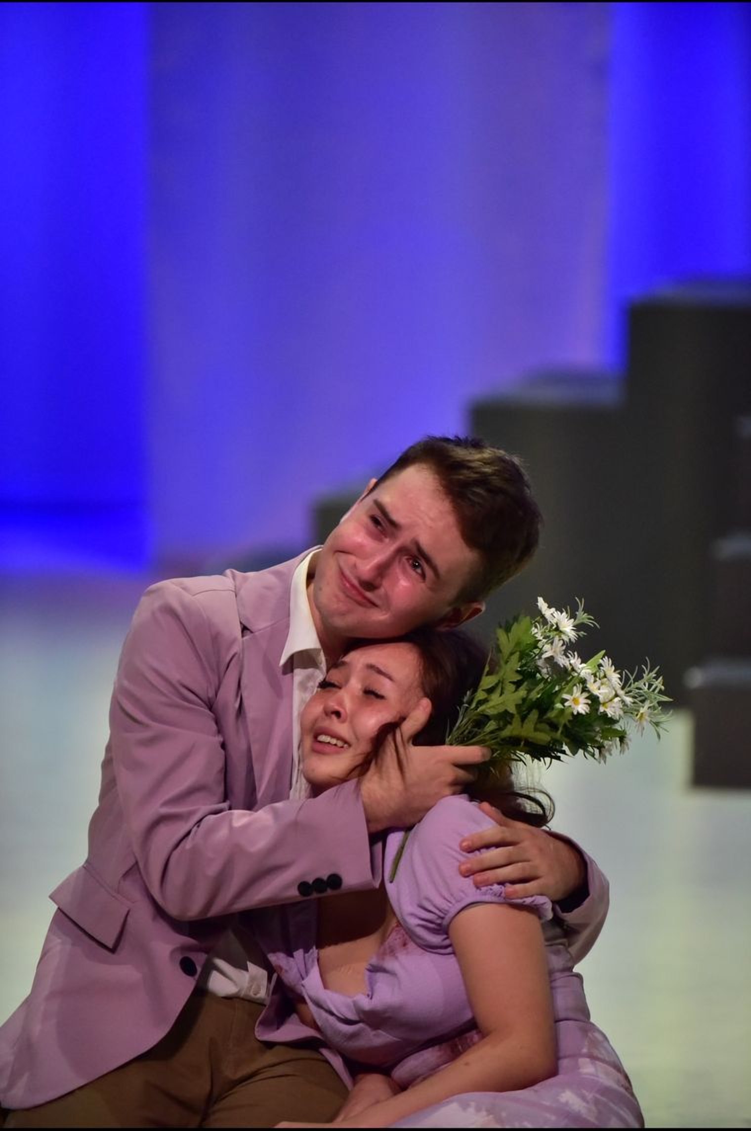 Andrei holds a weeping scene partner, a bouquet in his hand